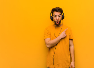 Young man listening to music pointing to the side