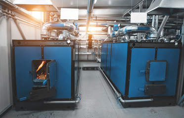 water-heating solid fuel boiler with open firebox and burning fire, installed in the boiler room. Blue toning with sunflare
