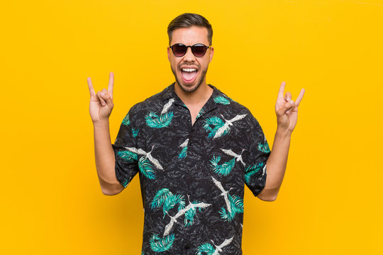 Young Filipino Man Wearing Summer Clothes Showing Rock Gesture With Fingers