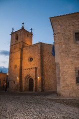 Fototapeta na wymiar Cobblestone street with church and gothic buildings at dusk in Caceres