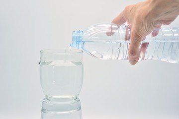 Botella de mano llenando un vaso de agua