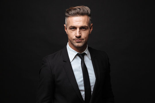 Portrait of serious handsome businessman dressed in formal suit posing and looking at camera