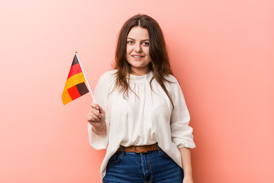 Young curvy plus size woman holding a germany flag happy, smiling and cheerful.