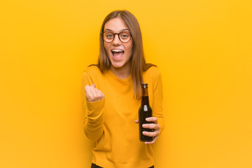 Young pretty caucasian woman surprised and shocked. She is holding a beer.