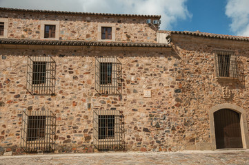 Fototapeta na wymiar Medieval building facade, with wooden door and barred windows at Caceres