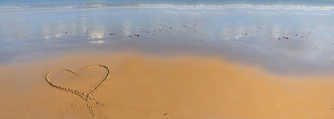 heart drawing on the sand in front of the sea