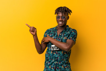 Young black rasta man wearing a vacation look smiling cheerfully pointing with forefinger away.