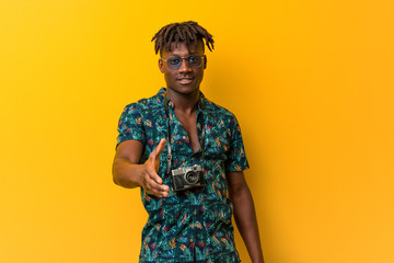 Young black rasta man wearing a vacation look stretching hand at camera in greeting gesture.