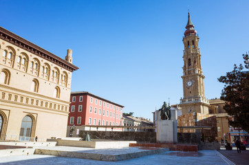 Fototapeta na wymiar Zaragoza, Aragon, Spain - February 14th, 2019 : Bell tower of La Seo cathedral of the Savior and Francisco de Goya monument at the Plaza del Pilar square.