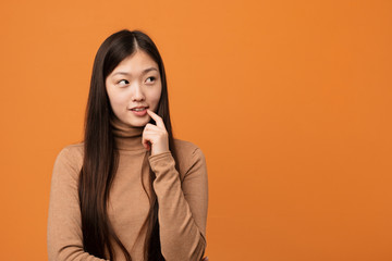 Young pretty chinese woman relaxed thinking about something looking at a copy space.