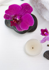 Spa or wellness setting with pink orchids ,candle and black stones.
