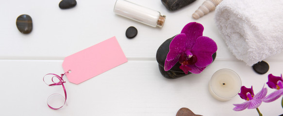 Fototapeta na wymiar Spa or wellness setting with pink orchids ,candle and black stones.