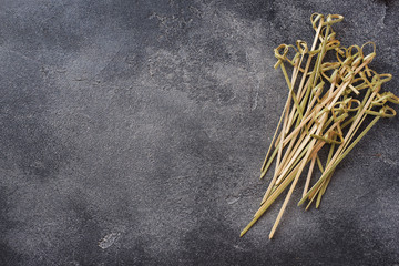 Pile of bamboo skewers on dark concrete background with copy space.