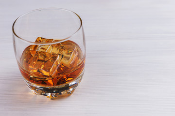 Glass of scotch whiskey isolated of a bright wooden table