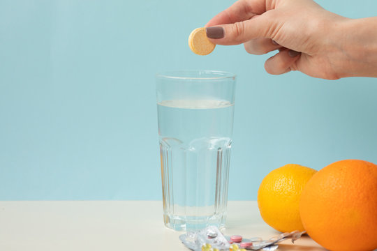 Glass with water on a white background with effervescent tablets vitamins. Vitamin C over blue background