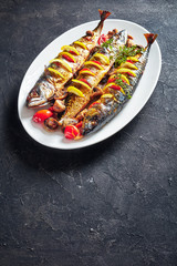 three whole roasted mackerel on an oval dish