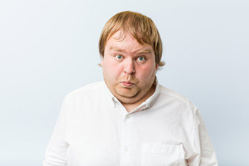 Obraz premium Young authentic redhead fat man shrugs shoulders and open eyes confused.