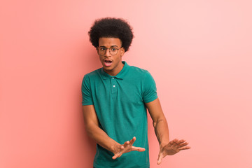 Young african american man over a pink wall rejecting something doing a gesture of disgust