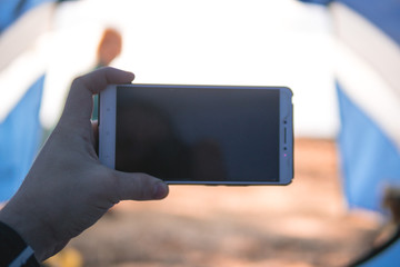Man traveler in a tent use smartphone gadget. Inside my tent, lake and camping, summer day, network, enternen, connection, connectivity, first person close-up view