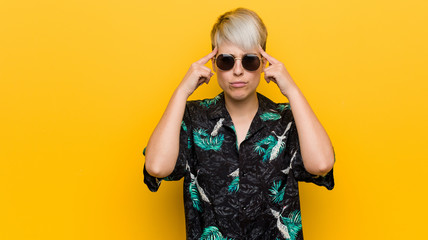 Young curvy woman wearing a summer look focused on a task, keeping forefingers pointing head.