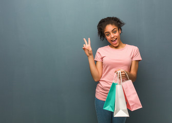 Young black woman doing a gesture of victory. She is holding a shopping bags.