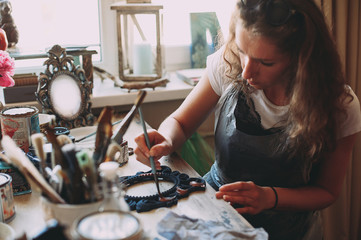 girl paints the frame with a brush. handwork. creation