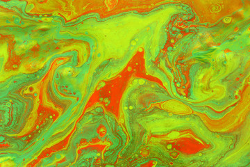 photography of abstract marbleized effect background. green and orange creative colors