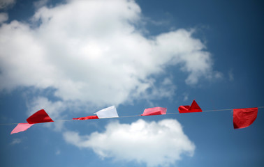Colorful flags of the street festival, fair or party against blue sky and white clouds. Minimalistic composition.