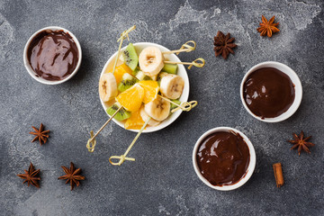 Obraz na płótnie Canvas Chocolate fondue with fruit on a dark concrete background. concept summer party.