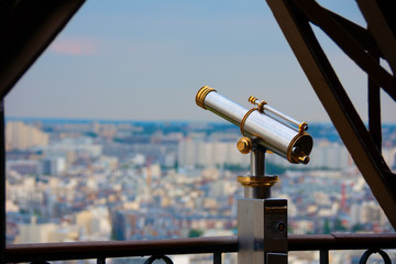 Telescope on the Eiffel Tower in Paris France overlooking the beautiful sprawling cityscape buildings filled with history and culture.
