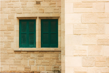 Green shutters on the old wall, made of stone