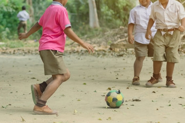 Student enjoy to play the old football with his friends on the ground in school.