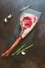 Top view of raw dry-aged marble beef steak Tomahawk on a kraft paper with spices. Flat lay, cooking...