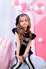 Fashion style little cute girl posing in studio with candy decoration for kids