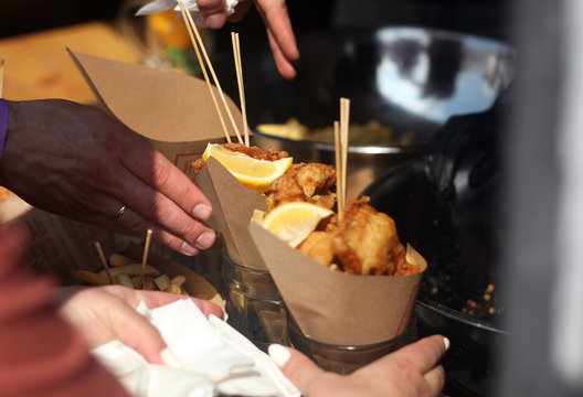 Street food festival. Picture of fish and chips with hands of event guests.