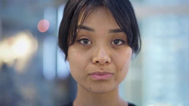 Portrait close up of funny emotional asian girl showing her tongue. Pretty playful black hair in tail asian girl looking straight at camera showing different emotions