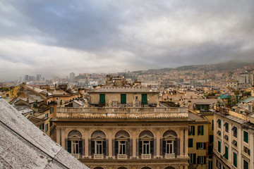 Fototapeta premium Panoramic view of Genoa rooftops taken from the top of the Cathedral of St Lawrence with Bendinelli Sauli palace (16th c., System of Rolli), in a rainy day with a dramatic cloudy sky, Liguria, Italy