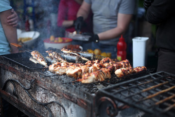 Grilled meat and fish cooked in the street food festival. Selective focus.