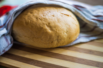 White, freshly baked bread in a towel on a wooden board