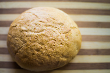 White, freshly baked bread in a towel on a wooden board