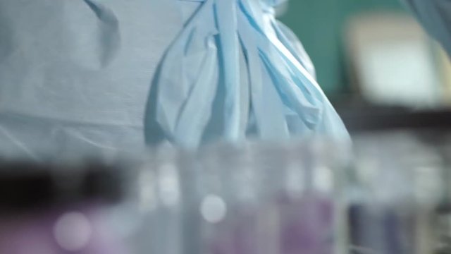 Production of beauty cosmetics. Laboratory assistent closes the jar with a purple sugar scrub cubes in it, and puts it away.