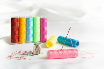 Needle, pins, thimble and colorful spools of thread