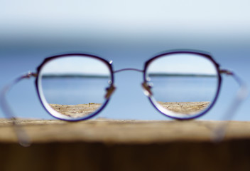 Round women`s glasses with a black frame lie on a stump