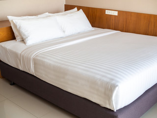 Clean white bedding with four white pillows in hotel bedroom