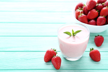 Smoothie in glass with strawberries on wooden table
