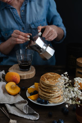 Female hands pouring coffe from moka coffe machine into a glass