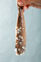 Female hand holds herring with onion, traditional dutch delicacy called hollandse nieuwe on turquoise background. European food concept with copy space.