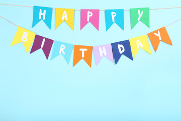 Paper flags with text Happy Birthday on blue background