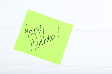 Paper with text Happy Birthday on white wooden table