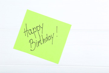 Paper with text Happy Birthday on white wooden table
